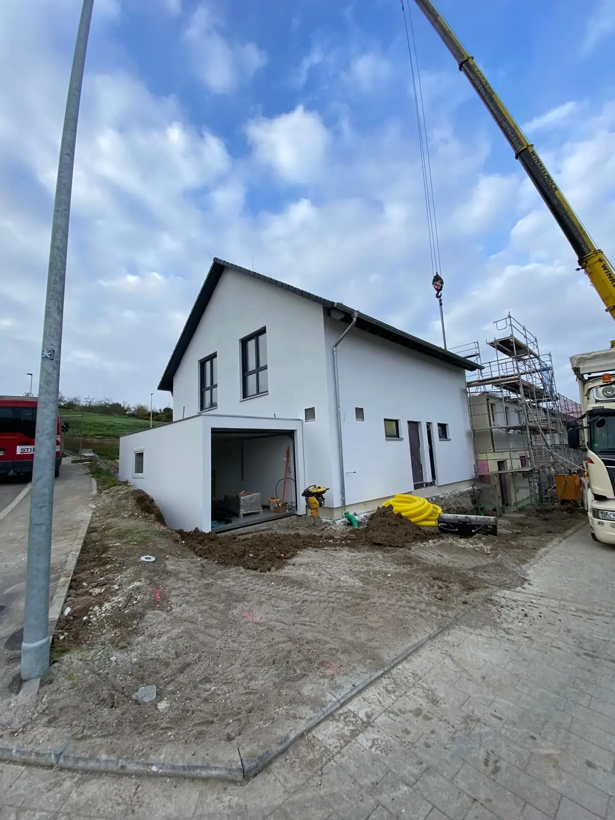 Vorher: Neubau im Rohbau mit Kran, offenem Erdreich und Baustellenmaterial